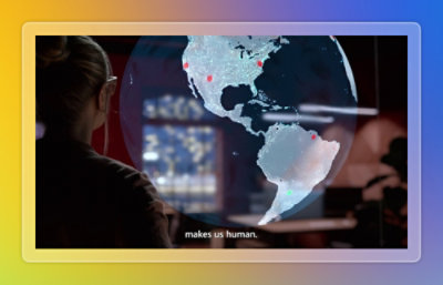 Person interacting with a large digital world map displayed on a transparent screen.