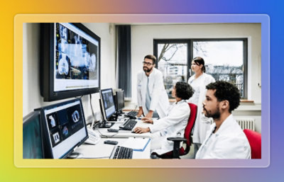 Medical professionals reviewing patient data on multiple monitors in a clinical workspace.