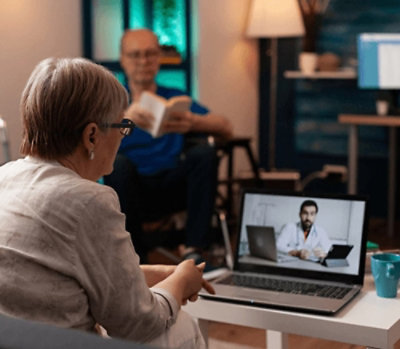 Person participating in a virtual medical consultation using a laptop at a desk.