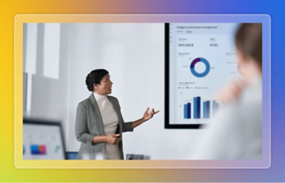 A person presenting data displayed on a screen behind them to coworkers.