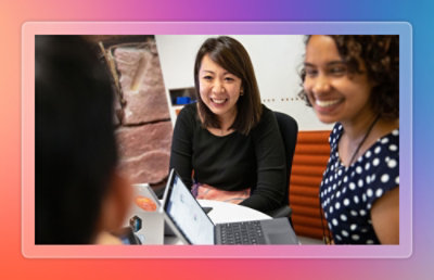 Colleagues collaborating around a tablet during a small group discussion in a workspace.