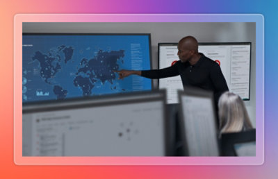 Presenter explaining insights using charts and a world map displayed on a large screen during a meeting.