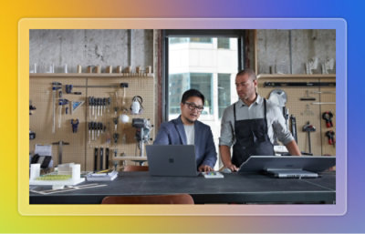 Two people working on laptop in a hardware workshop.