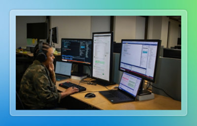 A person sitting at a desk with several computers.