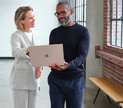 A man and woman look at a laptop together.