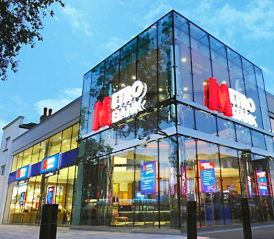 Exterior view of a modern glass‑fronted retail bank building with illuminated signage at street level.