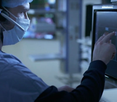 A person wearing a face mask working on a computer.