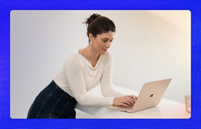 立ってノート PC を見ている女性。