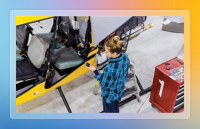 An image of a woman near a small helicopter doing something on phone.