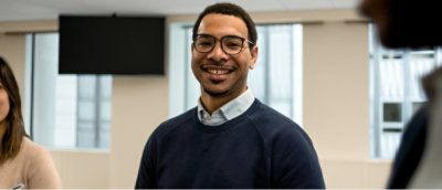 A person wearing specs looking at the camera