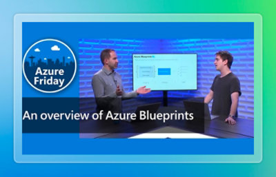 A man and a woman are seated in front of a computer screen displaying a blue circle with white text and a city silhouette.