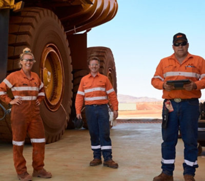 A group of people in orange overalls standing in front of large tires