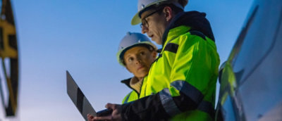 A person and another person wearing hard hats and yellow jackets