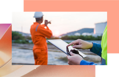 Osoba koja koristi tablet i druga osoba u šlemu pokazuju na fabriku