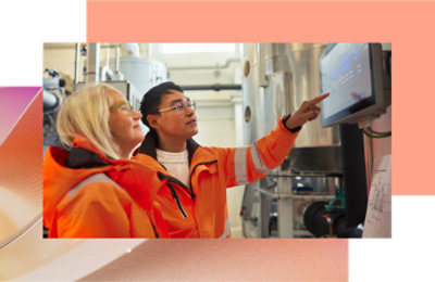 Dve osobe u narandžastim prslucima pokazuju na ekran