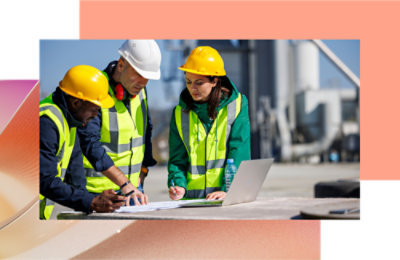 Grupa ljudi koja nosi bezbednosne prsluke i šlemove gleda u računar