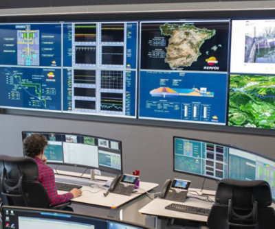 Osoba sedi za stolom ispred nekoliko monitora