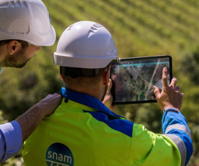 A person in hardhats looking at a tablet