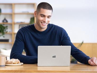 Eine Person, die an einem Tisch sitzt und einen Laptop verwendet.