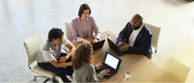 Eine Gruppe von Personen, die mit Laptops an einem Tisch sitzen.