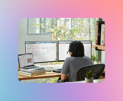 Een persoon die aan een bureau met meerdere computers zit