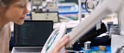 Osoba, která drží papír před notebookem