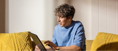 A man sitting in a sofa looking at a laptop.