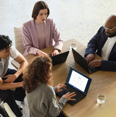 Four people in a meeting working on laptops