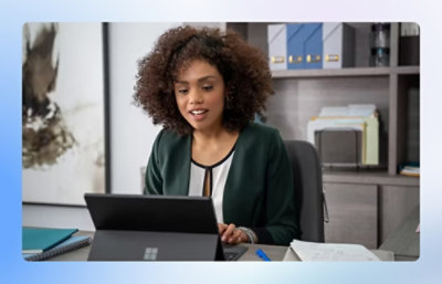 Person working on a laptop at a desk with notebooks and files.