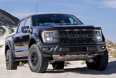 Black off-road pickup truck parked on a sandy desert landscape.