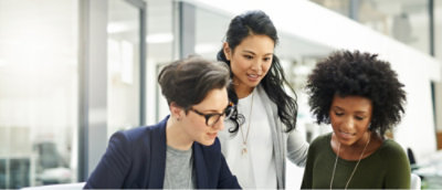 Three people, dressed casually, are engaged in a collaborative discussion at a desk in an office environment
