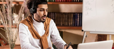 A man wearing headset and working with laptop