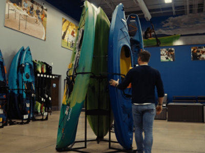 一个人站在商店里的皮艇旁边