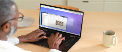 Person typing on a laptop at a desk with a mug nearby.