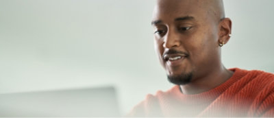 A person wearing a red sweater is looking at a screen.