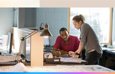 Two people working in an office with a green background.