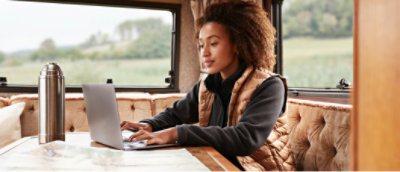 Een vrouw die op een laptop werkt en een witte jas draagt
