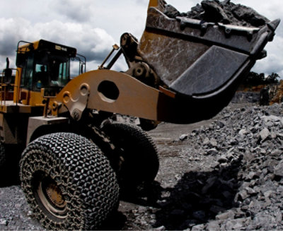 A bulldozer is positioned in the center of a rocky pile