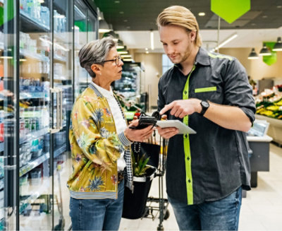 A man and woman stand together in front of refrigerator discussing