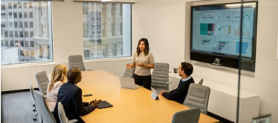 一個人站在一群圍坐在桌旁的人前方。