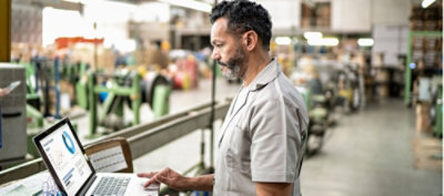 一名男子在工廠環境中使用膝上型電腦。