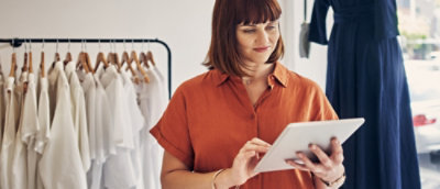 一人站在一排白襯衫前，手持平板。