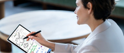Person in a white blazer uses a stylus on a tablet, viewing a document with colored annotations.
