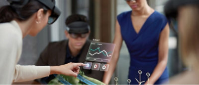 Personas con gafas de realidad aumentada interactúan con una pantalla digital que muestra un gráfico.