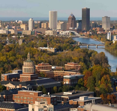 Aerial view of city skyline with river, bridges, and tree‑lined campus buildings in the foreground.