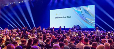 A large group of people in a large room with visible chairs and stage lighting.
