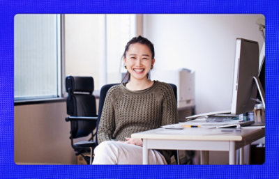 Woman looking ate the camera and smiling while sitting in an office envirnment