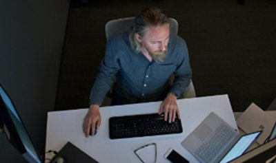 A bird’s eye view of a person working at their desk with multiple screens and a laptop