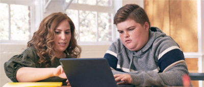 A child and a person looking at a computer.