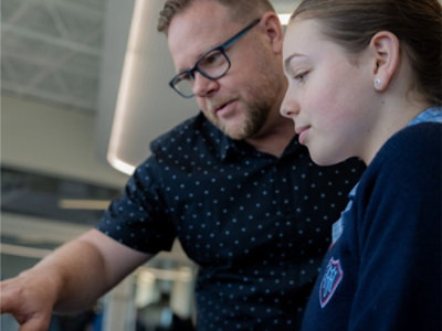 A person and another person looking at a computer screen.